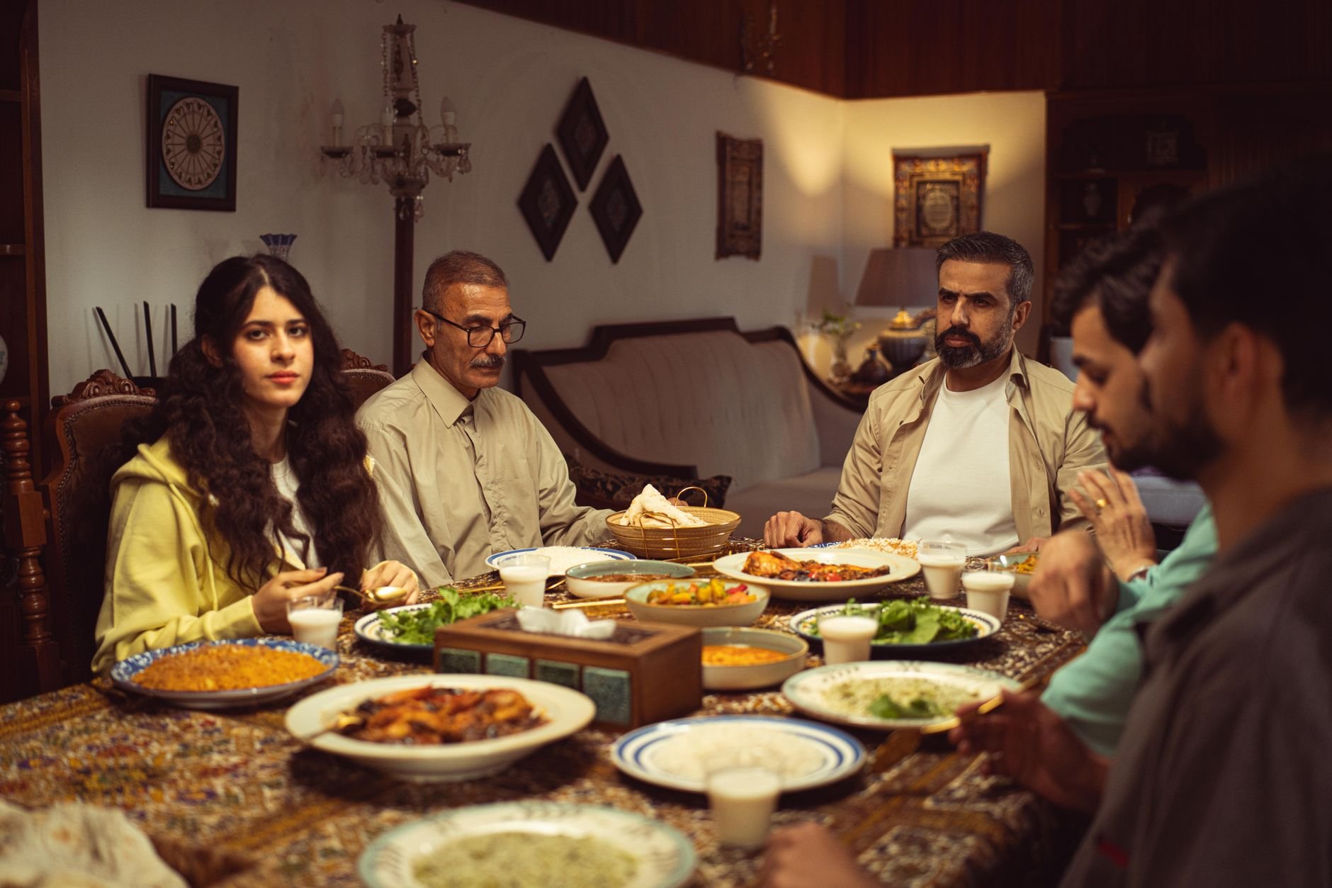 A family gathers at home for a traditional dinner, sharing diverse dishes and warm company