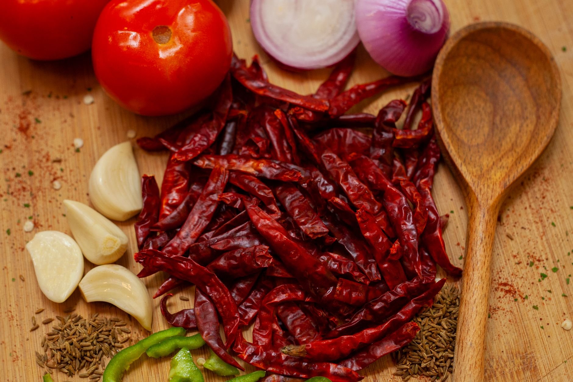 Vibrant chili peppers, garlic, and spices arranged on a wooden board